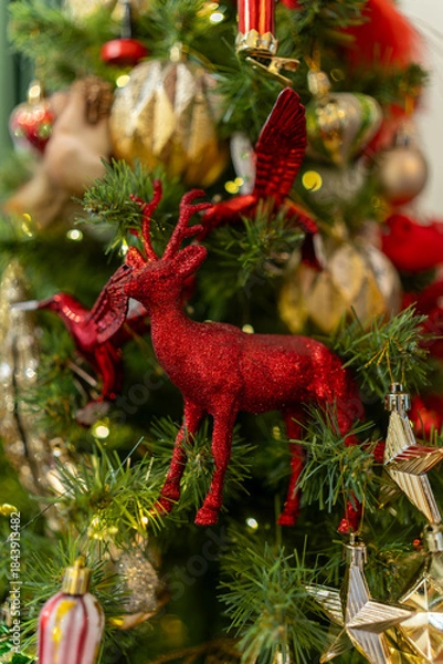 Obraz Sparkling red reindeer ornament on holiday Christmas tree with golden decorations
