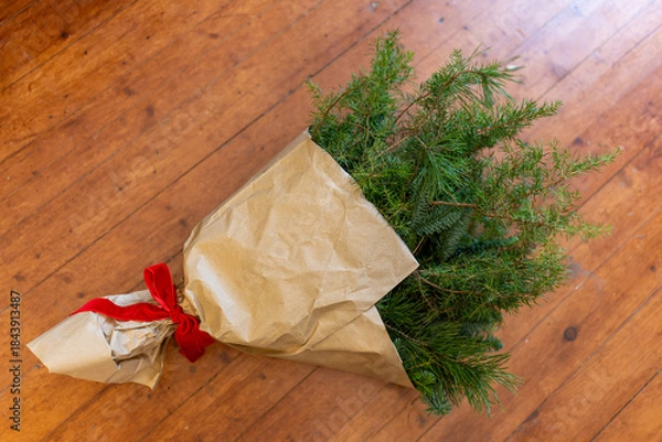 Obraz Christmas greenery bouquet with red ribbon on wooden floor
