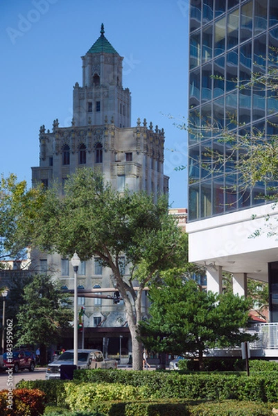 Obraz Architectural Contrast: Historic Snell Arcade Tower With Ornate Details Beside Modern Glass Building in City Center in St. Petersburg, FL. Urban scene featuring a historic, ornate tower adjacent to a 