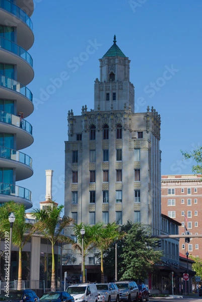 Obraz Architectural Contrast: Historic Snell Arcade Tower With Ornate Details Beside Modern Glass Building in City Center in St. Petersburg, FL. Urban scene featuring a historic, ornate tower adjacent to a 
