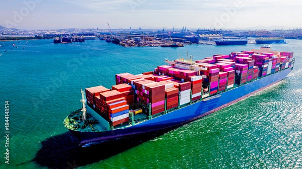 Fototapeta container ship, fully loaded with goods, sails out to sea, delivering products to various locations