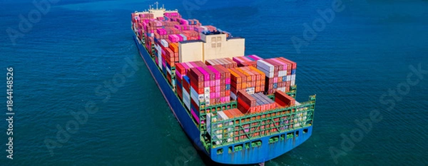 Fototapeta container ship, fully loaded with goods, sails out to sea, delivering products to various locations