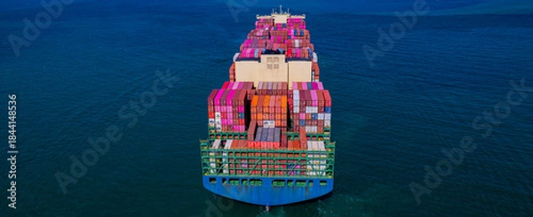Fototapeta container ship, fully loaded with goods, sails out to sea, delivering products to various locations