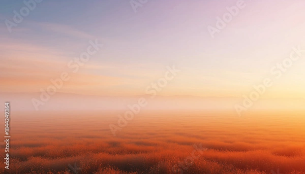Obraz A serene sunrise over a misty landscape, with warm orange and yellow hues illuminating the horizon.