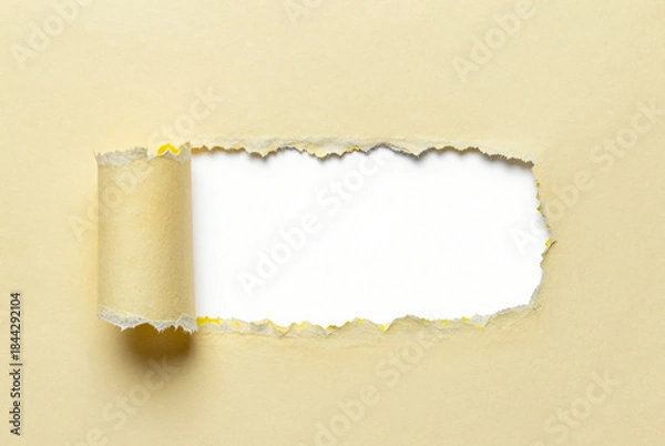 Fototapeta Torn piece of paper on a beige background.