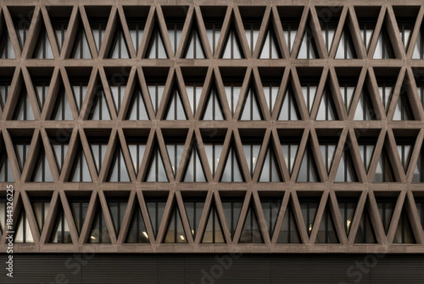 Fototapeta Modern building facade with shaped geometric structure and glass windows.