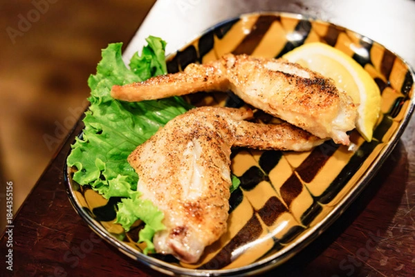 Obraz 香ばしく焼き上げられた手羽先（鶏肉）とレモンのクローズアップ