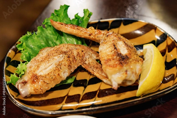 Obraz 香ばしく焼き上げられた手羽先（鶏肉）とレモンのクローズアップ