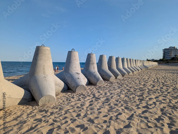 Obraz Weathered tetrapod blocks guard the sandy beach.