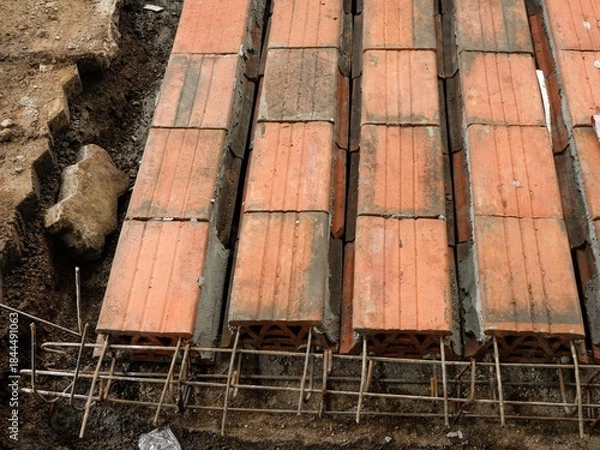 Fototapeta High-angle close-up of hollow clay blocks sometimes called slabs set horizontally on a rebar framework, showing the initial stages of a floor or beam construction.