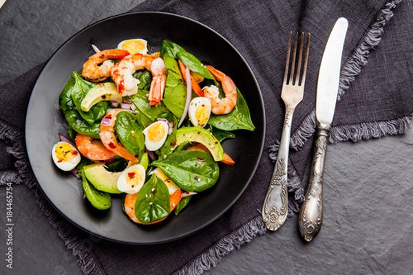 Obraz Fresh, healthy salad with shrimps, spinach and avocado on a black background. Top view
