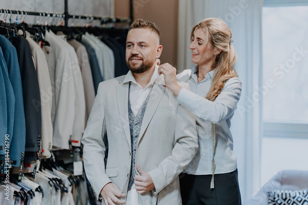 Fototapeta Friendly fashion expert assisting a customer with suit selection in a modern menswear boutique offering premium service and stylish clothing