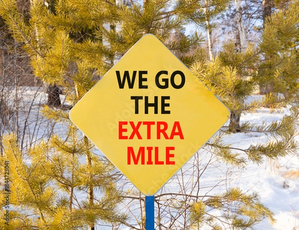 Fototapeta Support, help we go the extra mile symbol. Concept words We go the extra mile on beautiful yellow road sign. Beautiful winter forest background. Business we go the extra mile concept. Copy space.