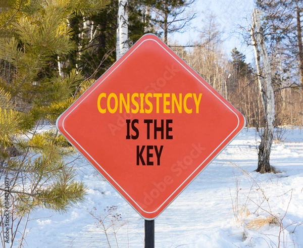 Fototapeta Consistency is the key symbol. Concept words Consistency is the key on beautiful red road sign. Beautiful winter forest background. Business consistency is the key concept. Copy space.