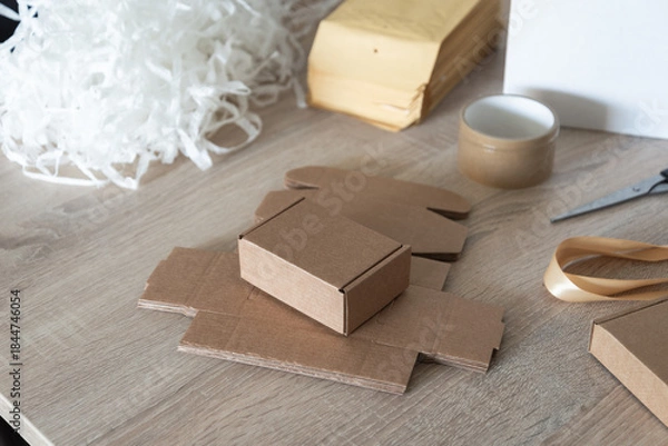 Fototapeta Small cardboard box with packing filler on work table