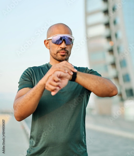 Obraz Portrait opf a young man prepering to exercise and run and looking at watch in sportwear posing for a portrait outdoors