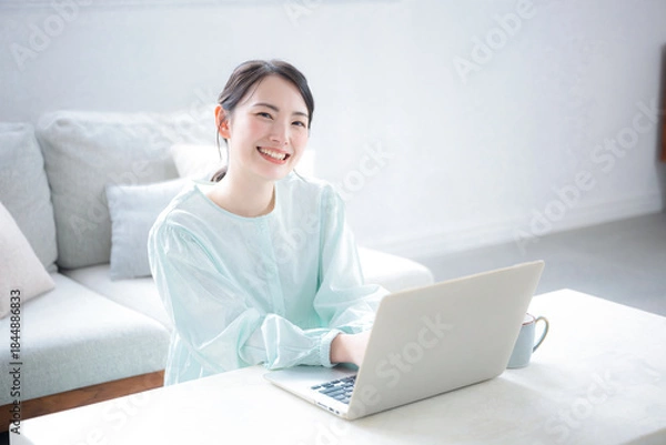 Obraz 座るパソコンを操作する女性　タイピングするカメラ目線