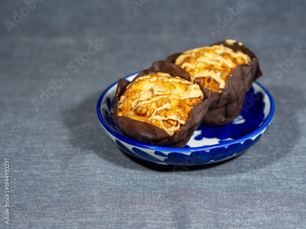 Fototapeta Muffins with nuts and cream filling in a blue bowl. Delicious dessert on the table. Calories and cholesterol