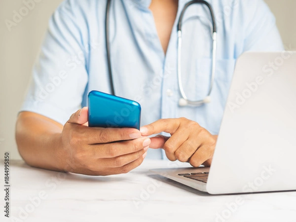 Obraz Doctor using smartphone for telemedicine at office desk.