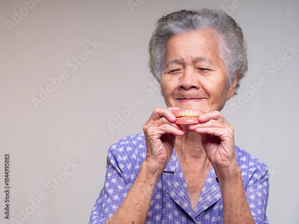 Obraz Elderly female showing denture and smiling gently.