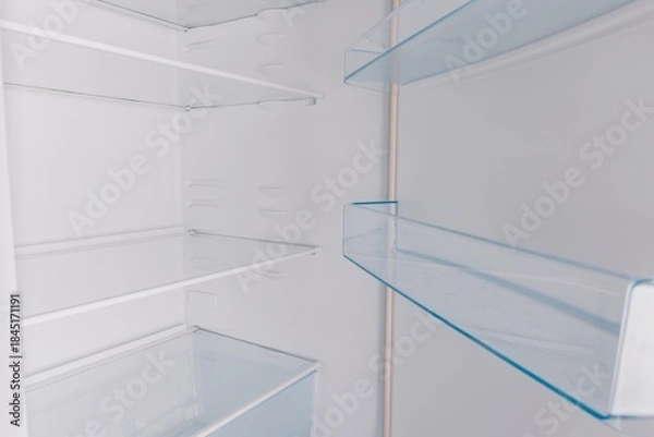 Obraz An Inside Look at an Empty Refrigerator Showcasing Its Spacious Shelves and Clear Glass Racks Perfect for Organizing Food and Beverages
