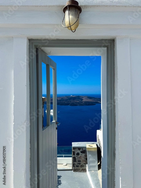 Obraz Stunning view from a door overlooking the Aegean Sea on a sunny day in Santorini, Greece with blue skies and distant islands in sight