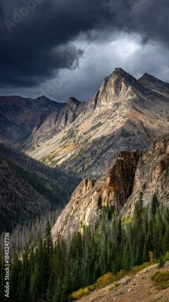 Obraz Dramatic Rocky Mountains Under Stormy Clouds with Sunlight.