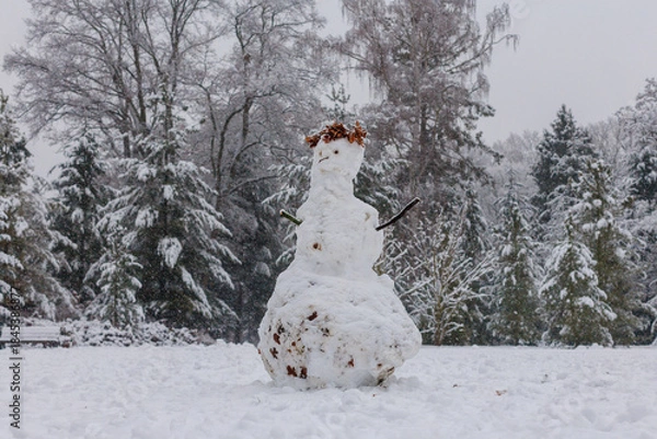 Fototapeta Real imperfect snowman in snowy winter forest during snowfall