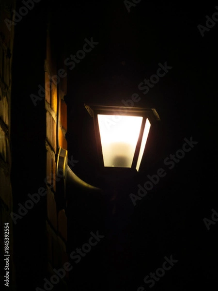 Obraz Bright Lantern Illuminates Dark Brick Wall at Night