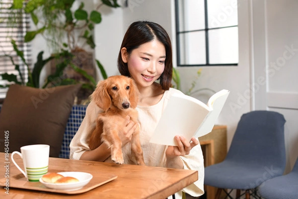 Obraz 自宅で犬と読書するアジア人の若い女性