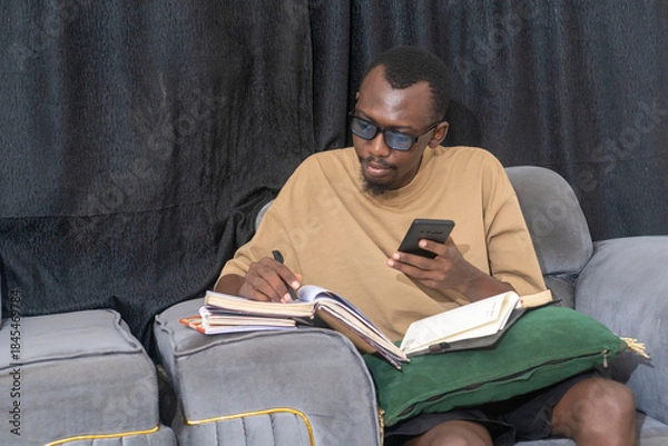 Obraz handsome african man using cellphone to do his assignment