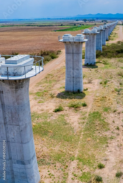 Fototapeta The concrete pillars/piers for the high-speed rail track are under construction at the unfinished construction site.