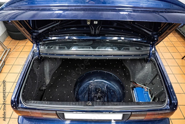 Obraz Car audio system installation: amplifier and wiring setup in a clean vehicle trunk. Professional customization and technical maintenance for premium car sound.