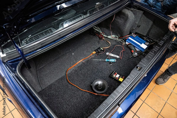 Obraz Car audio system installation: amplifier and wiring setup in a clean vehicle trunk. Professional customization and technical maintenance for premium car sound.