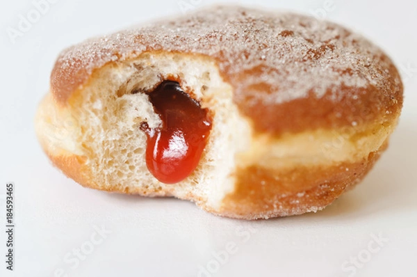 Fototapeta German fried donut, so called Krapfen, Berliner or Pfannkuchen, filled with rose hip jam and dusted with cinnamon sugar, traditionally eaten at carnival and at New Year's Eve on white background