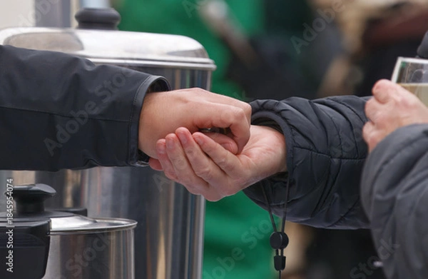 Obraz Close-up of a cash transaction at hot drinks stall at Naplavka market, vendor returns coins to customer, capturing the authentic moment of buying, selling, and paying with cash in busy Prague market.