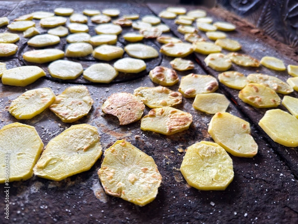 Obraz Potato slices drying on rustic stove surface