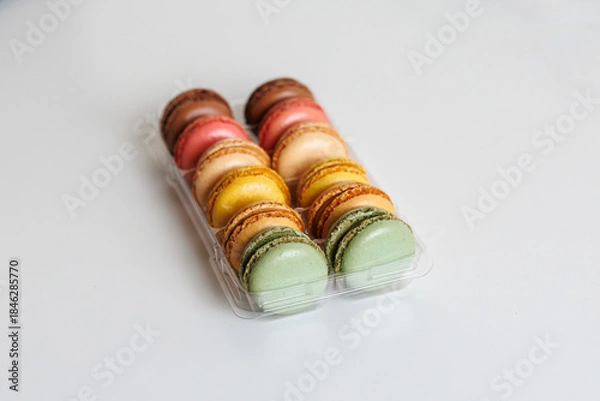 Fototapeta Colorful macarons assortment in plastic tray on white background