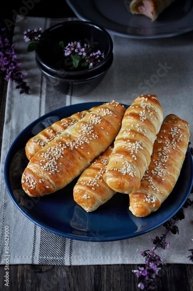 Fototapeta On a wooden table on a plate a bunch of sausages in a dough