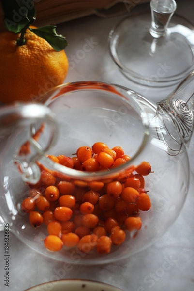 Obraz Sea buckthorn in a transparent teapot on the table