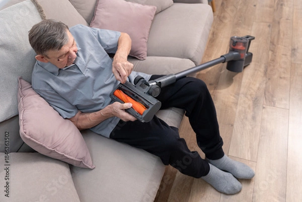 Obraz Elderly man checking vacuum cleaner at home