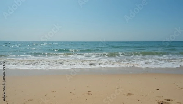 Fototapeta A clear horizon, soft waves, and a sandy beach backdrop