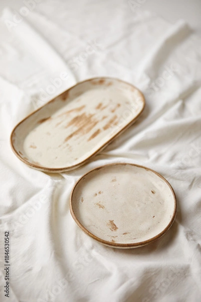 Obraz Ceramic plates on white textile background. Handmade ceramics.