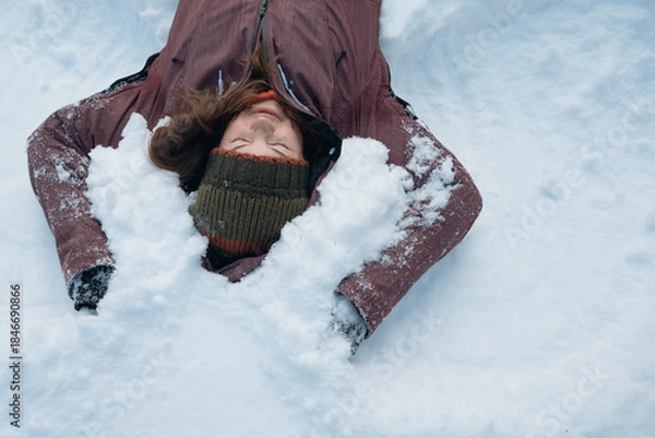 Obraz Mid adult woman enjoying of lying on snow in winter with closed eyes