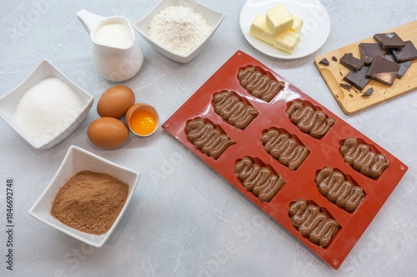 Fototapeta Process of making chocolate  madeleines Ingredients for chocolate cookies. Chocolate French Madeleine cookies. Top view.
