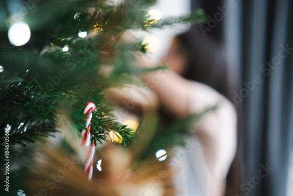 Fototapeta Blurred unidentifiable child near Christmas tree expressing abstract joy, anonymous holiday atmosphere concept