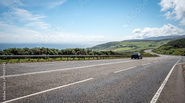 Fototapeta Scottish Highland road trip. A quiet coastal road running through the Highlands of Scotland on a bright summers day.