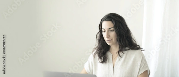 Obraz Female patient sits at home having a virtual medical consultation with a doctor through a video call on her laptop.
