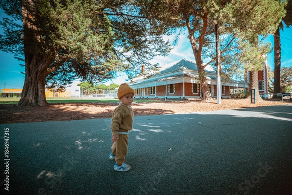 Obraz Charming toddler exploring a park with a picturesque house in the background.