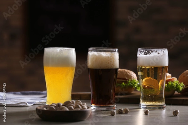 Fototapeta Glasses with different sorts of beer on table in sport bar